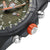 Détail de montre homme : boîtier noir avec couronne orange et boutons métalliques sur le côté