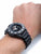 Herren-Armbanduhr am Handgelenk: schwarzes Band, schwarzes Zifferblatt mit Tauchskala.