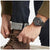 Montre pour homme au poignet avec bracelet noir et cadran sombre.