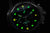 Bracelet de montre pour homme avec boîtier noir et index vert lumineux sur cadran sombre