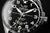 Herrenuhr-Zifferblatt Nahansicht: schwarzes Design, silberne Zeiger, Space Race Logo
