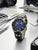 Zeppelin Herrenuhr auf Schreibtisch, blaues Zifferblatt, schwarze Lünette, braunes Lederarmband