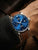 Herrenuhr mit blauem Zifferblatt, braunem Lederband und Datumsfenster, am Handgelenk