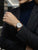 Damen-Armbanduhr mit weißem Zifferblatt und braunem Lederband am Handgelenk