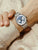 Zeigt Damenuhr mit silbernem Metallarmband, blauem Zifferblatt und Chrono-/Hilfsanzeigen