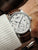 Herrenuhr am Handgelenk mit braunem Lederband und hellem Analogzifferblatt