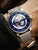 Herrenarmbanduhr mit blauem Zifferblatt, sichtbarem Automatikwerk und silbernem Mesh-Armband