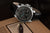 Herrenarmbanduhr mit schwarzem Lederband, rundes Gehäuse und schwarzes Zifferblatt