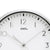 Gros plan d'une horloge murale : cadran blanc avec logo AMS et aiguilles