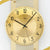 Nahaufnahme Funk-Wanduhr: goldenes Zifferblatt mit schwarzen Zeigern und Ziffern