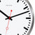 Détail de l'horloge murale : cadran blanc, aiguilles noires, trotteuse rouge, bordure argentée