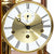 Gros plan sur l'horloge de table : mouvement doré, cadran blanc avec index des heures romains